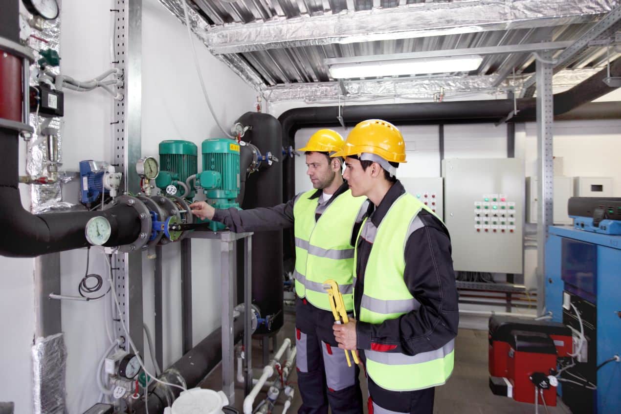 Zwei Techniker analysieren Rohrleitungen in Innenanlage mit installiertem selbstbegrenzendem Heizband zur Temperaturregelung