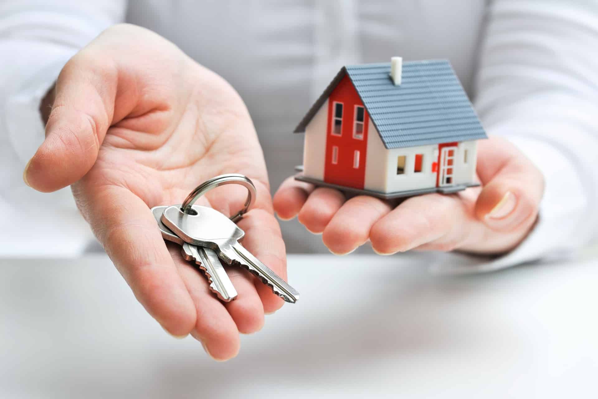 Hände halten Hausschlüssel und kleines Modellhaus | Anwalt Baurecht Nürnberg
